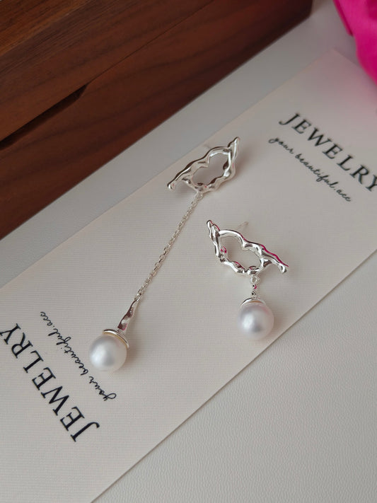 Tui in flight pearl earrings showing silver bird charms and two hanging white pearls