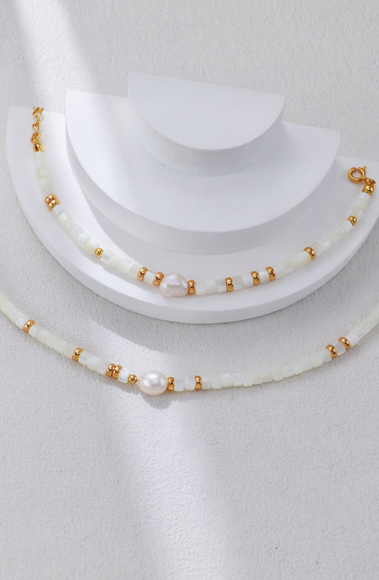 White shell pearl necklace with gold beads and a clasped pearl accent.