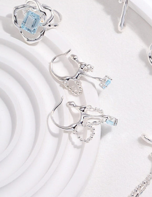 Silver-tone earrings with blue square stone drops and pavé flower-style caps