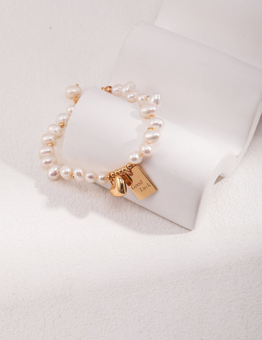 Pearl bracelet on display with gold Good Luck tag charm
