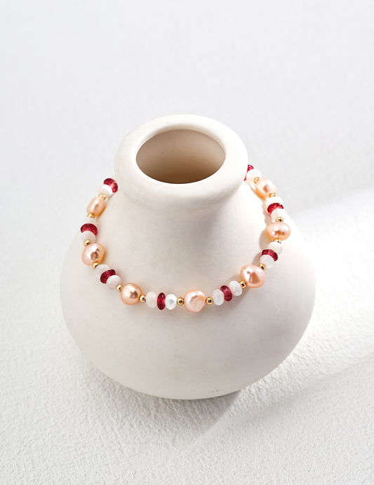 Pink pearl and red bead bracelet on display bust with gold-tone clasp chain