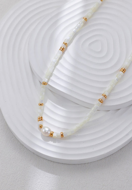 White shell bead necklace with gold spacers and a single pearl centerpiece.