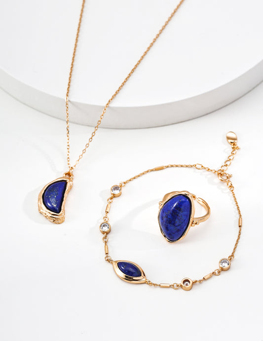 Gold-tone teardrop lapis pendant necklace on white pedestal with chain