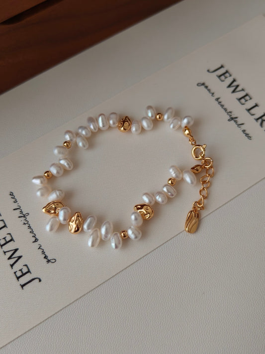 Freshwater pearl bracelet with gold charms and clasp, on jewelry card