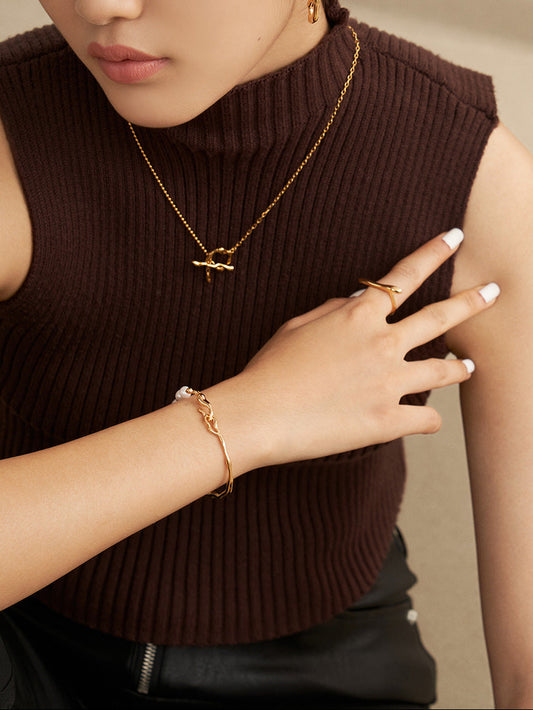Gold-tone pearl chain bracelet with round pearl beads and wavy link cuff on wrist