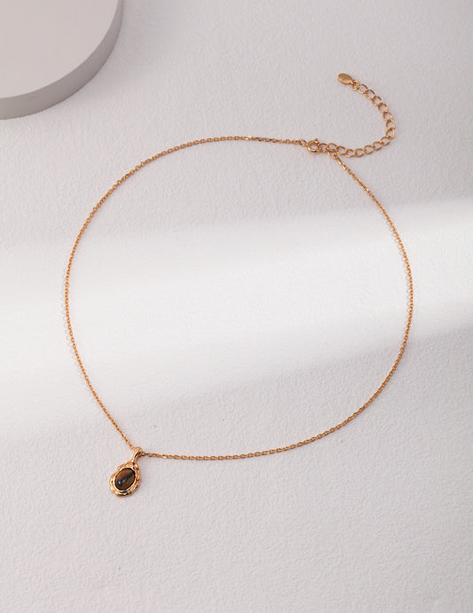 Gold-tone bead-link chain necklace with small oval dark stone pendant