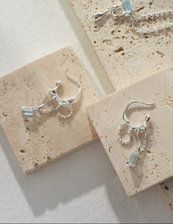 Silver-tone hoop earrings with blue rectangular stones and small chain fringe