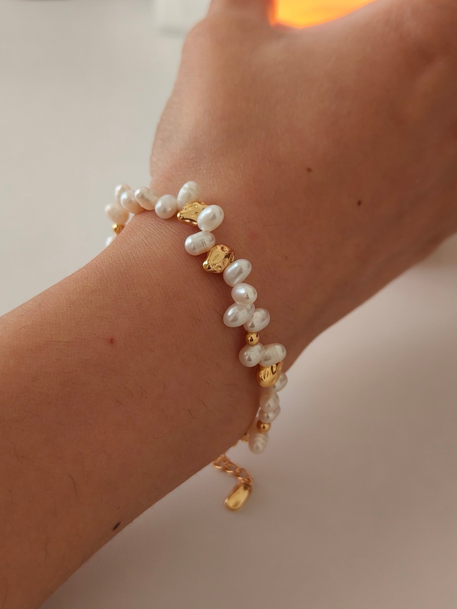 Freshwater pearl bracelet on wrist with gold bead stations and pendant charm