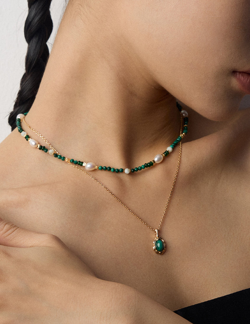 Gold-tone layered necklaces with green bead strand, pearls, and oval green stone pendant