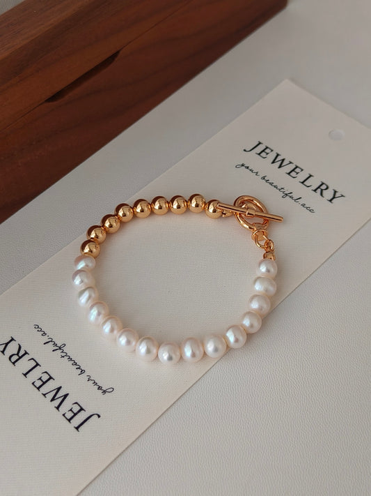 Pearl bracelet with white freshwater pearls and gold toggle clasp with small dangling chain