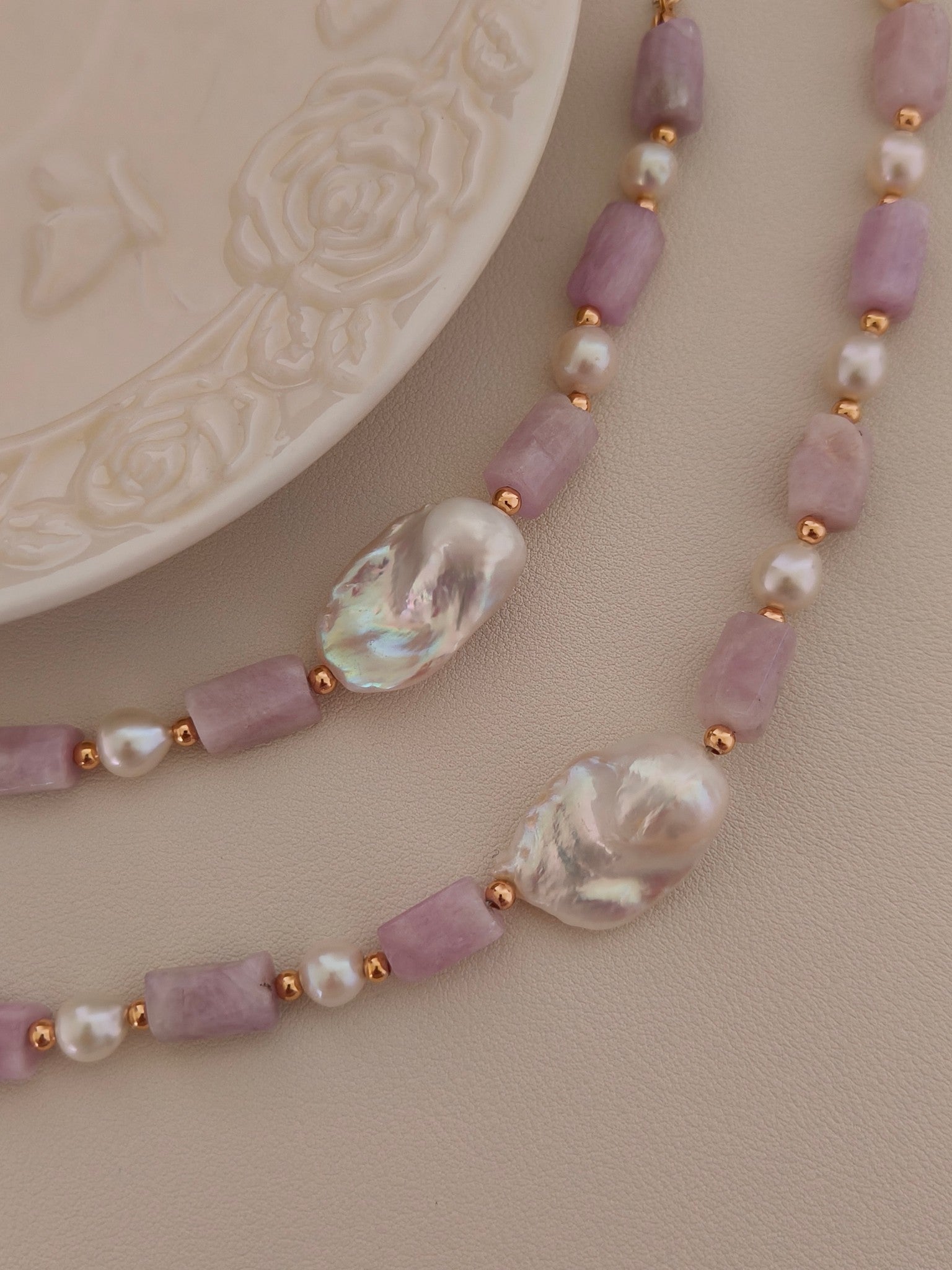 Baroque pearl and kunzite necklace close-up: lavender stone bars and iridescent pearls on gold