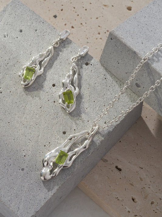 Silver necklace pendant with green peridot teardrop, close-up on chain