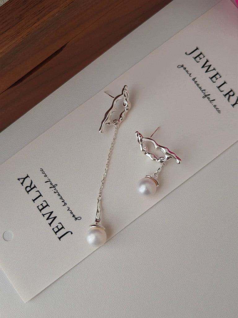 Bird charm pearl earrings featuring a flying tui with long chain and white drops