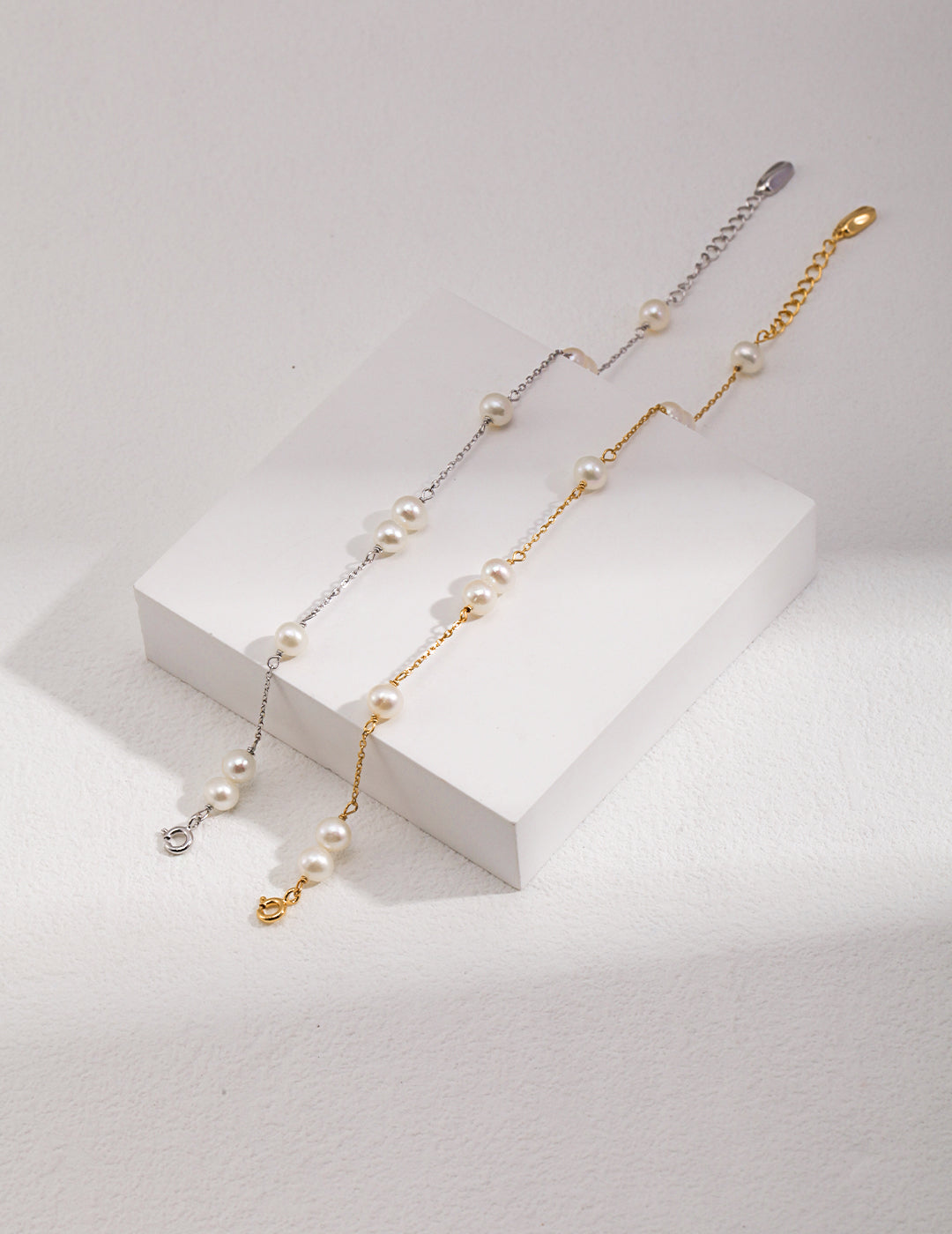 Pearl chain bracelet pair in silver and gold tones with round white beads and charms