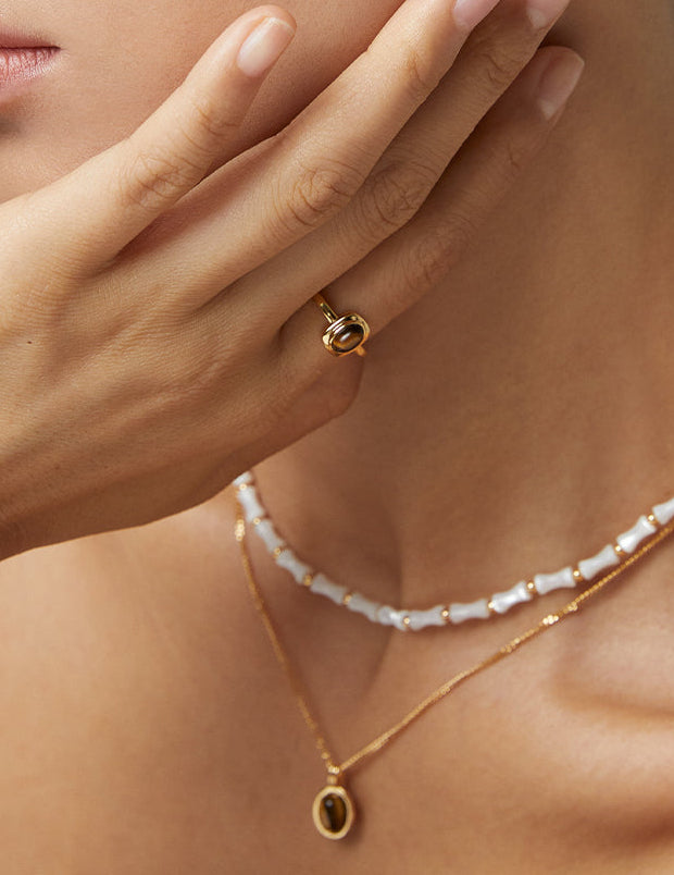 Gold-tone tiger eye ring on finger, round stone bezel visible in close-up