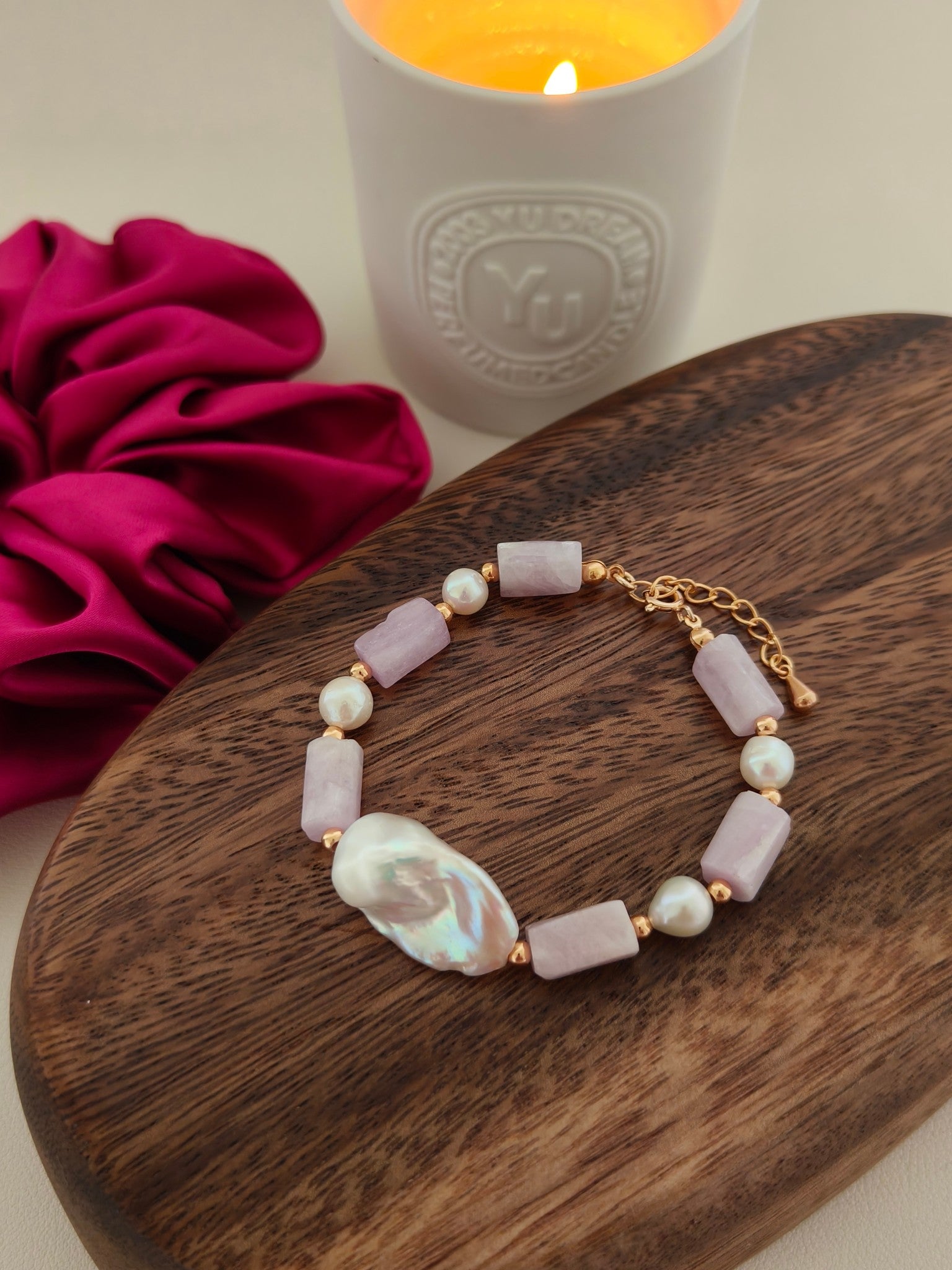 Purple stone and pearl bracelet with gold chain, shown on round wooden tray