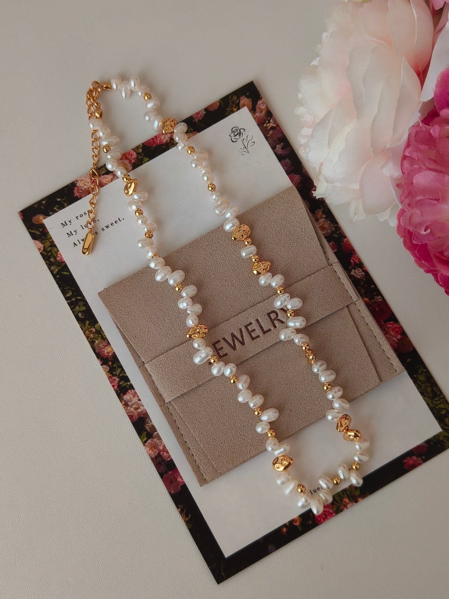 Freshwater pearl necklace on jewelry card with gold-tone charms and pendant