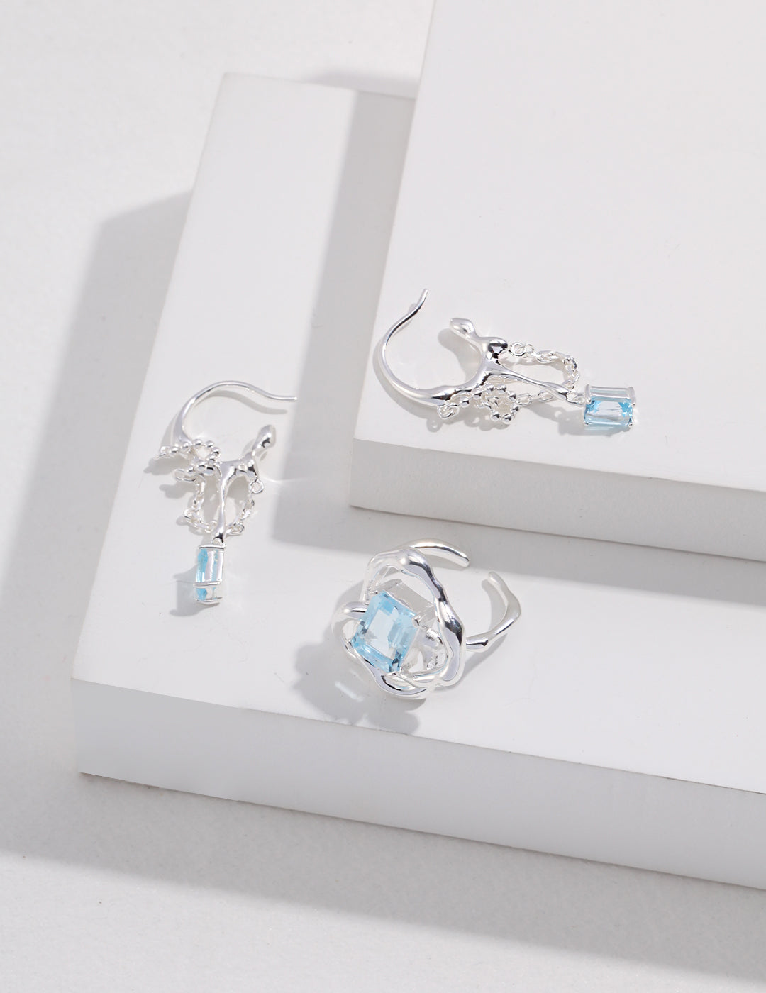 Silver-tone earrings featuring a blue square centerpiece and teardrop-like dangles