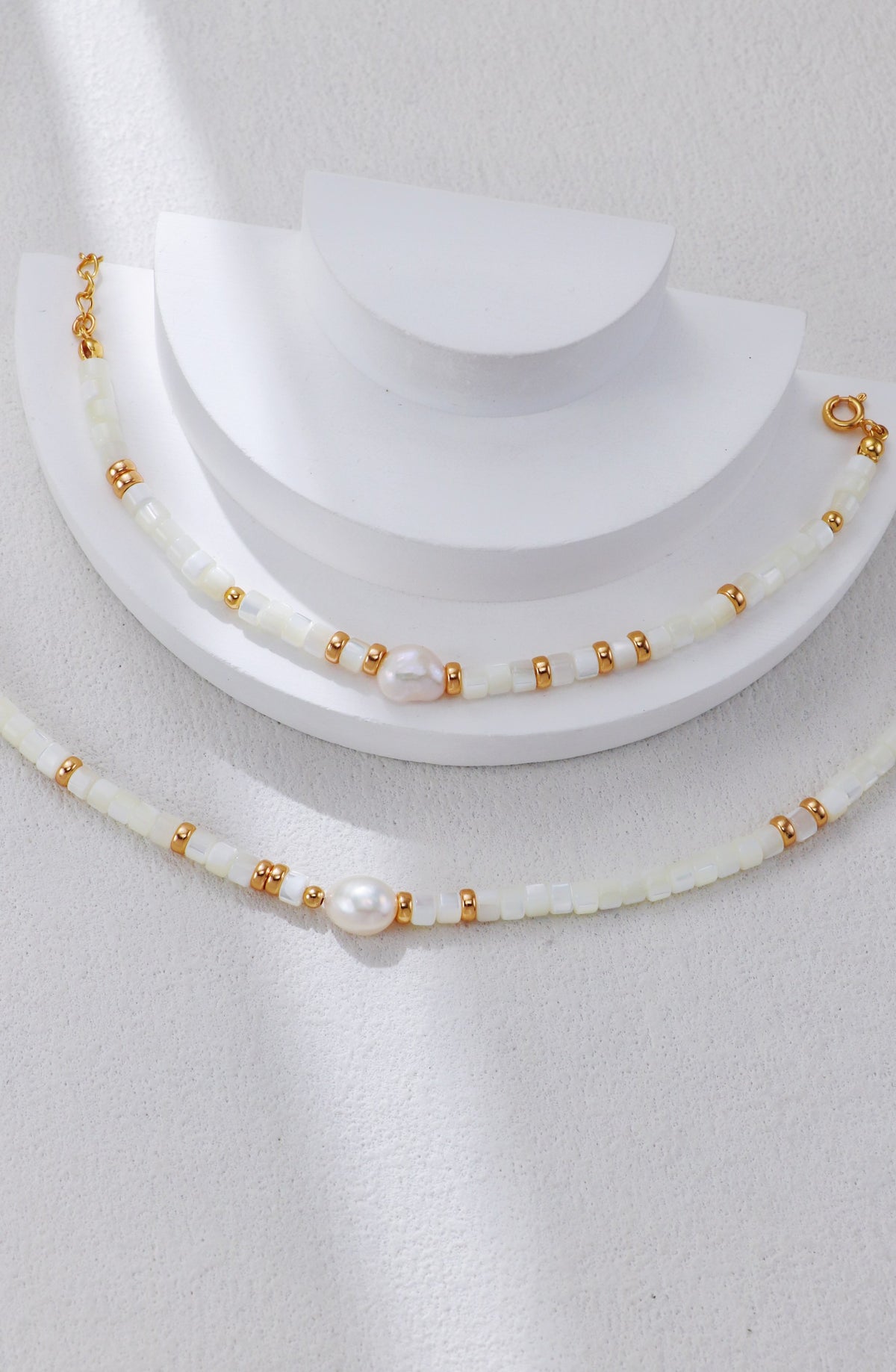 White shell pearl necklace with gold beads and a clasped pearl accent.