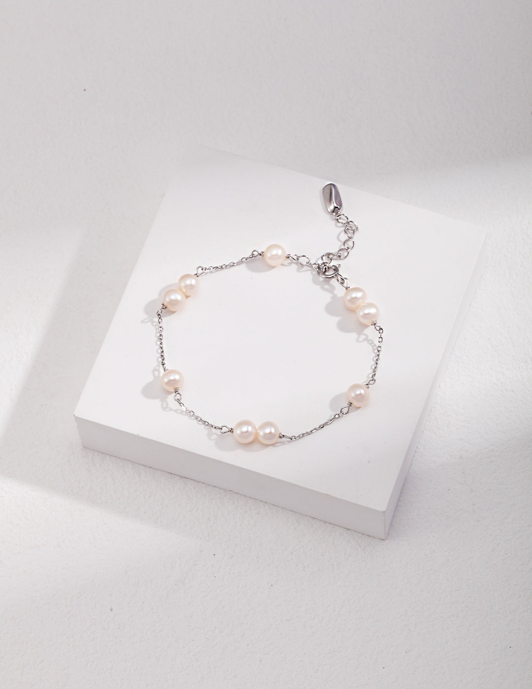 Sterling silver pearl bracelet with round white beads and small dangling charm
