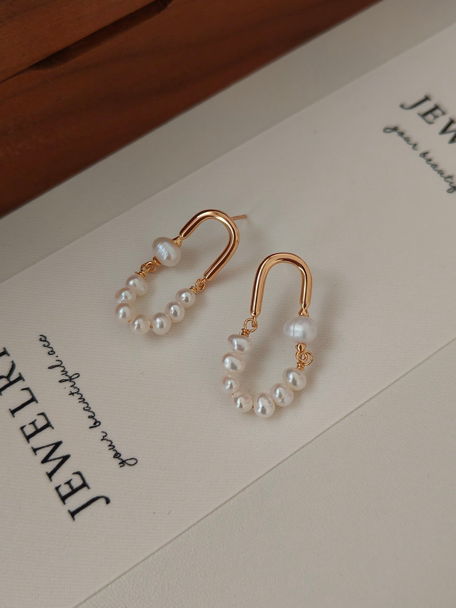 Rose gold hoop pearl earrings with white bead clusters hanging from curved hooks