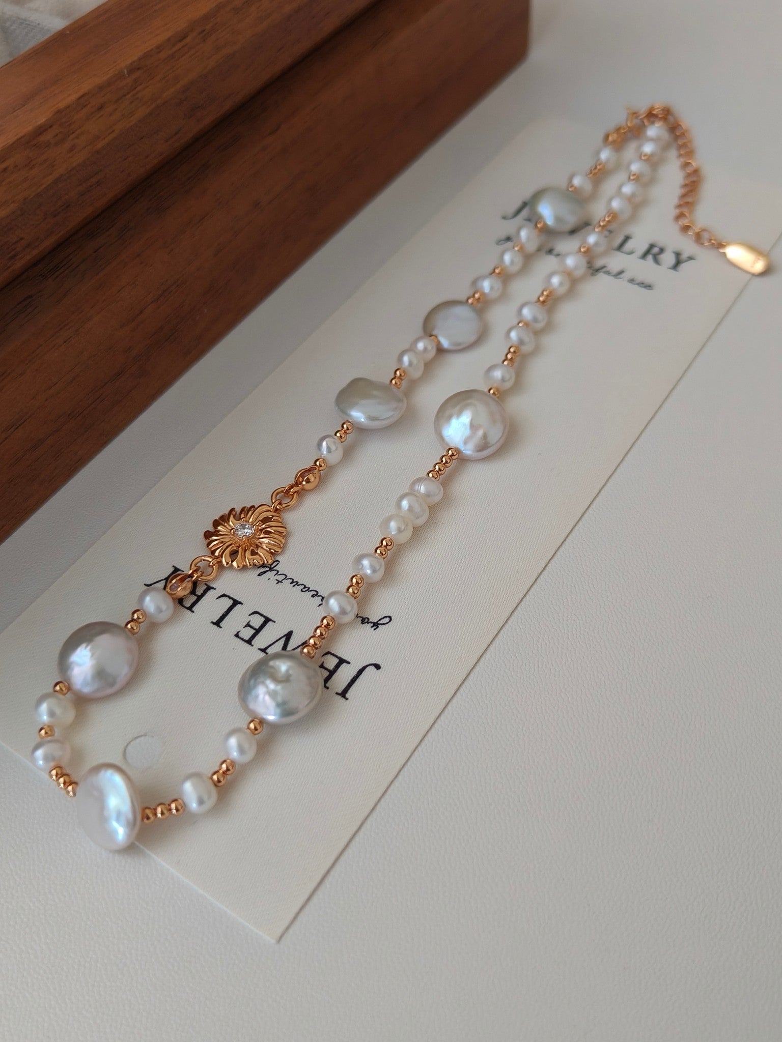 Gold-tone freshwater pearl necklace with multiple pearl strands and floral charm