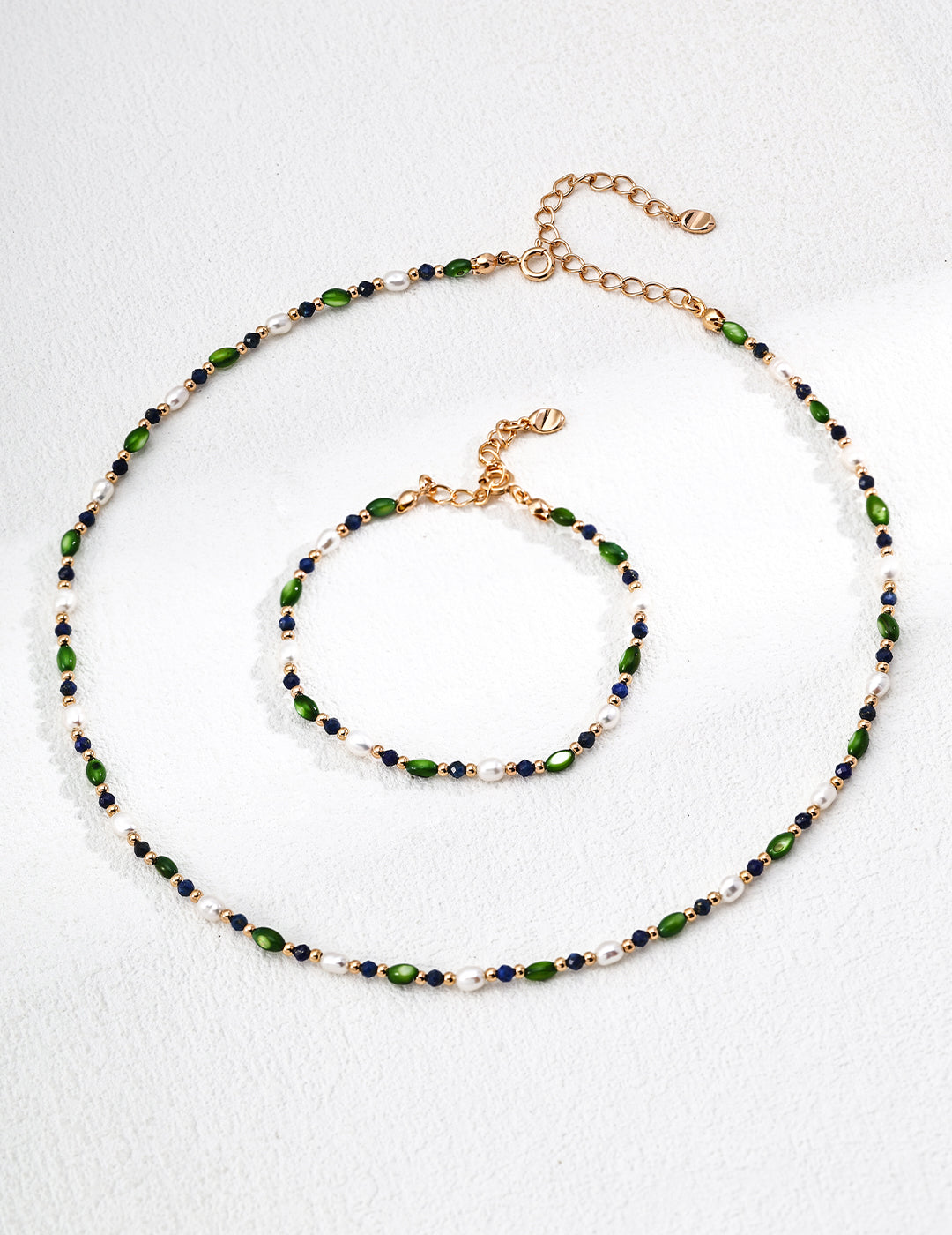 Beaded bracelet with green and blue beads, white pearls, and gold chain clasp, plus looped strand