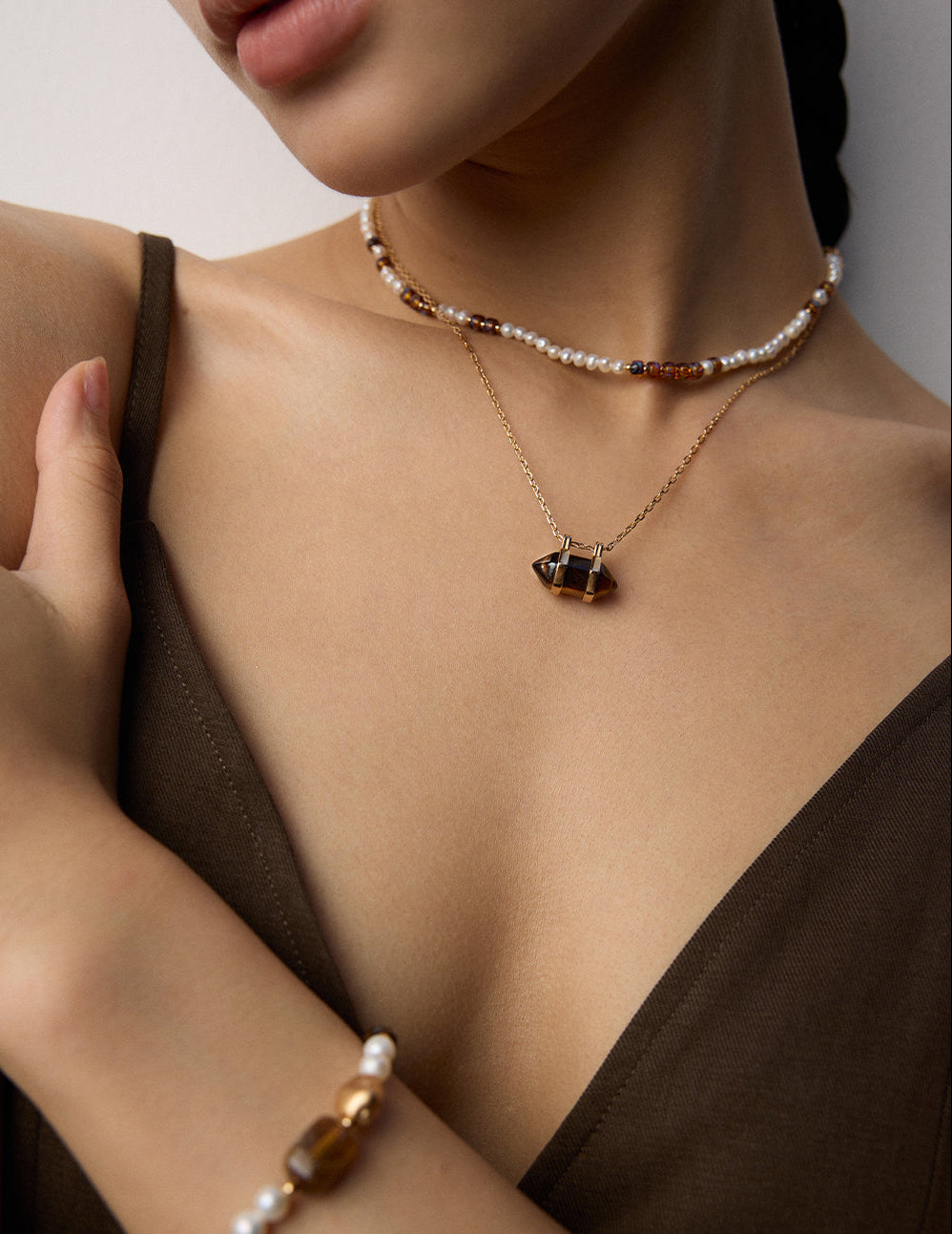 Pearl-bead necklace with gold geometric pendant charm on a thin gold chain