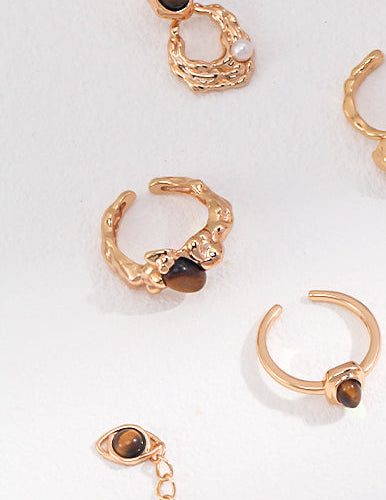 Gold-tone ring set with tiger eye stones and small pearl-like accents, mixed designs