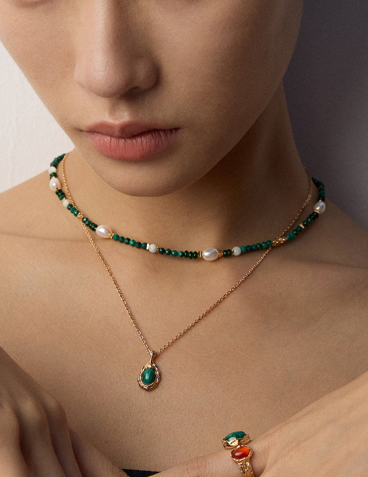 Gold-tone layered necklaces with green beaded choker and oval green stone pendant
