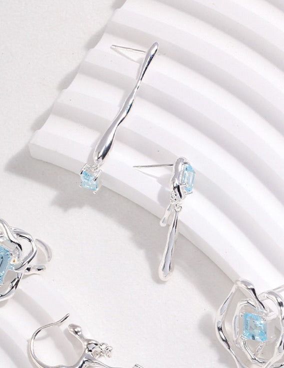 Silver-tone drop earrings with blue square gemstones and curved elongated stems