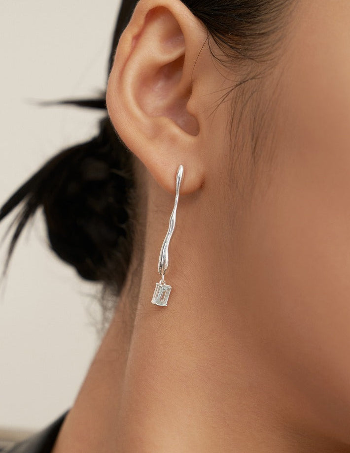 Silver-tone drop earrings with blue square gemstone on slim hook, on ear