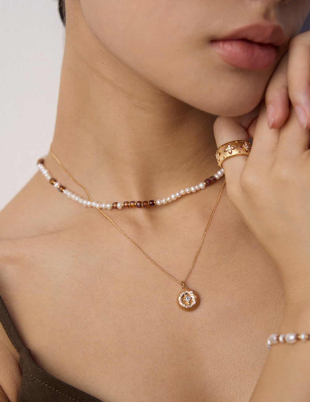 Layered pearl bead choker necklace with gold pendant and small brown bead accents