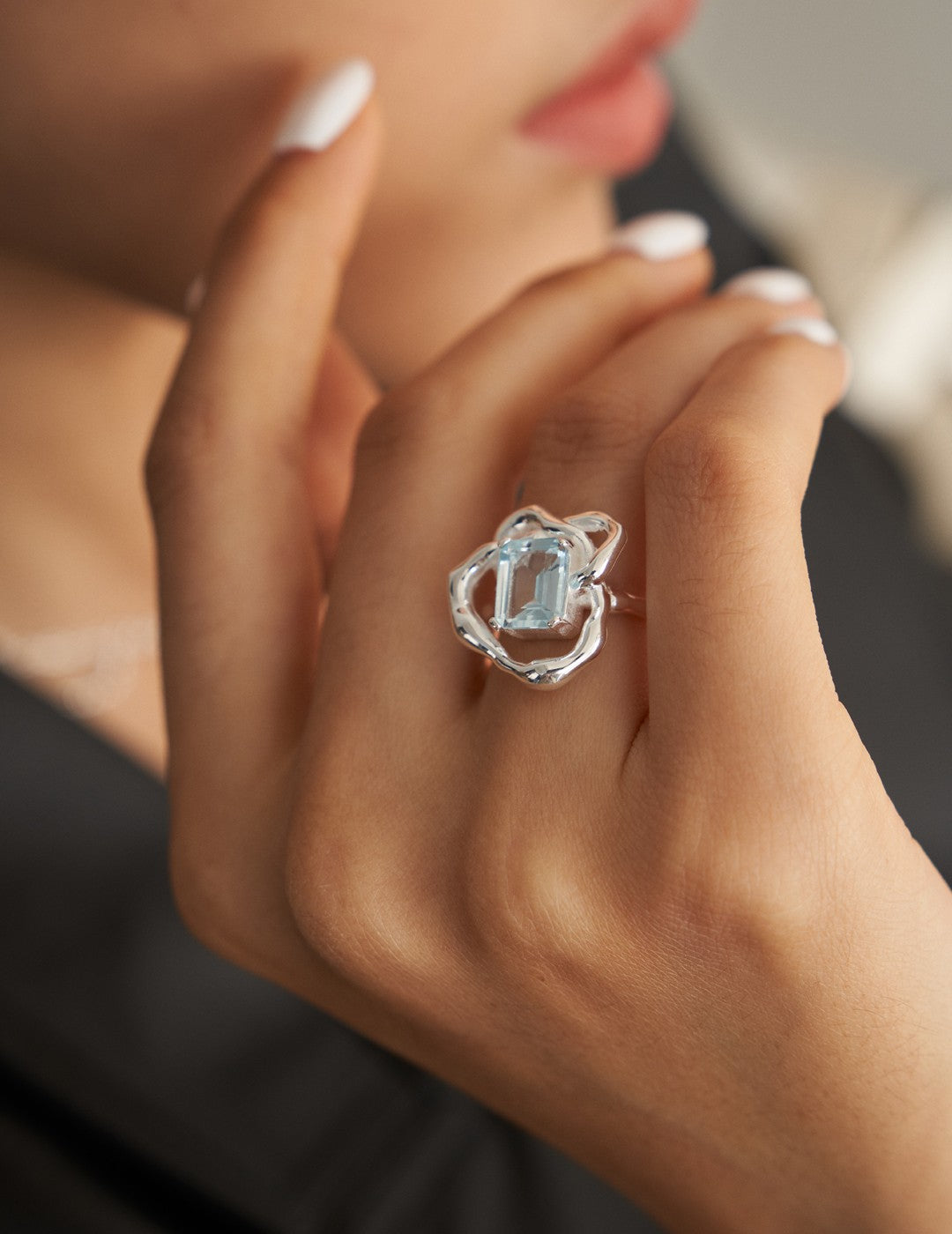 Silver ring with rectangular light-blue gemstone on openwork band, on hand