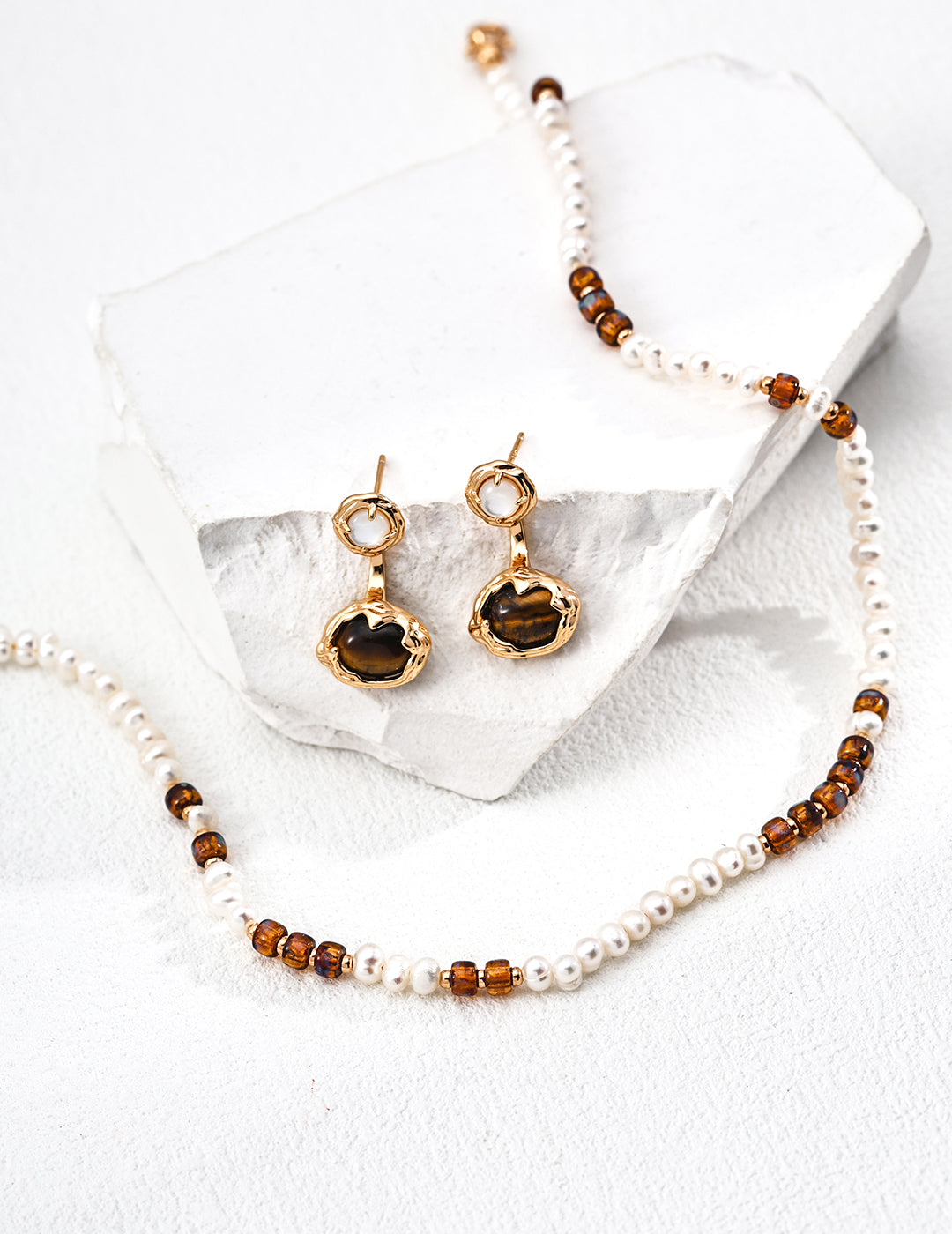 Pearl and amber bead necklace with gold clasp, with earrings and bracelet nearby