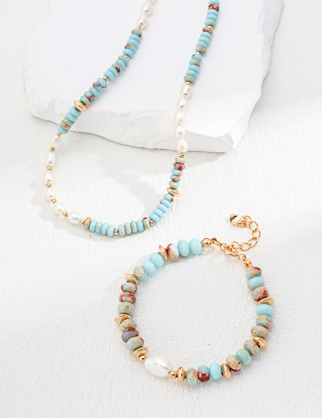 Turquoise heishi and freshwater pearl necklace with gold-tone clasp on white display