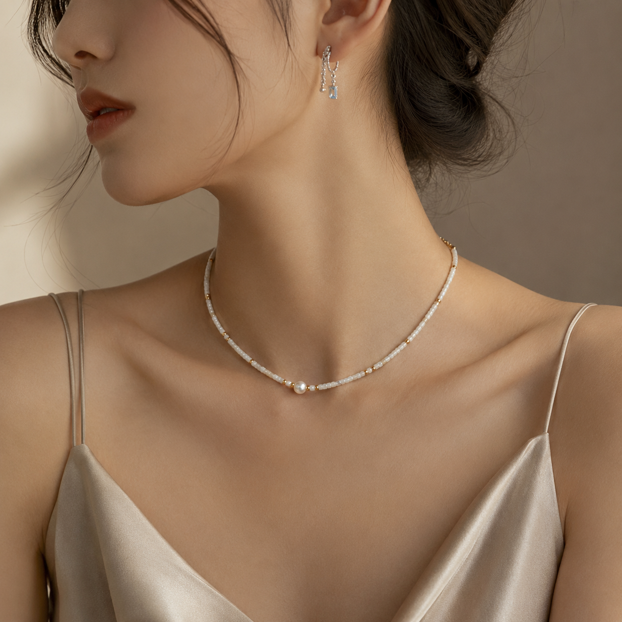 White shell bead necklace with gold spacers and a central pearl on the model.