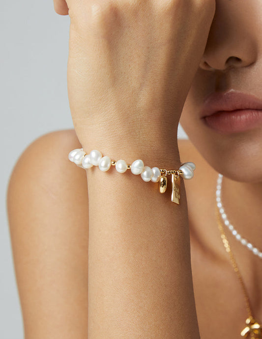 Pearl bracelet on wrist with gold Good Luck charm and dangling tag