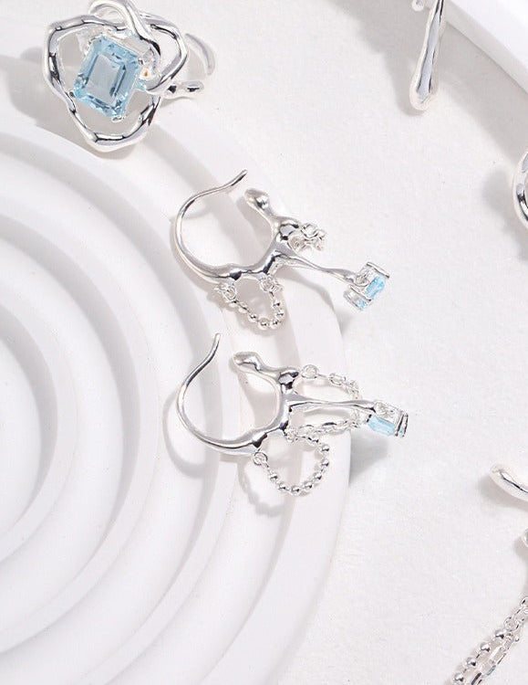 Silver-tone earrings with blue square stone drops and pavé flower-style caps