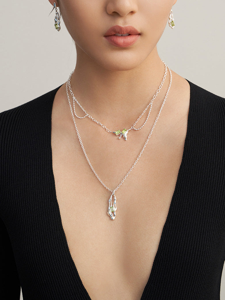 Layered silver necklace with green peridot charm and teardrop pendant