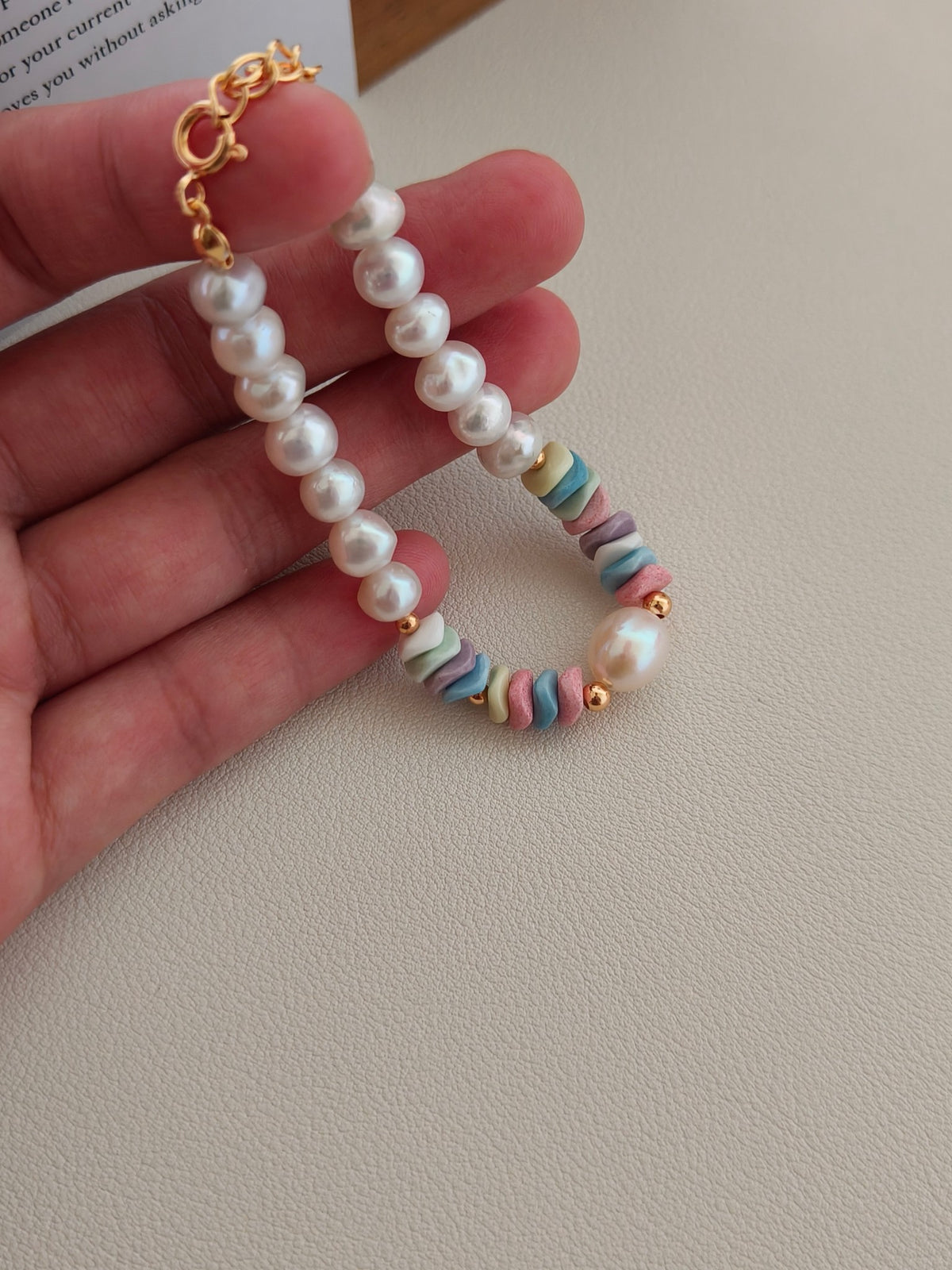 Freshwater pearl bracelet held in hand with pastel rainbow stone beads and clasp