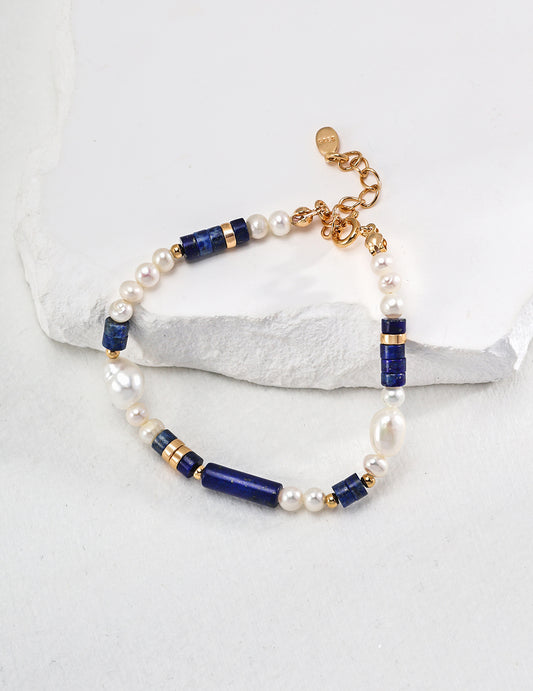 Freshwater pearl and lapis bead bracelet with gold clasp on stone surface