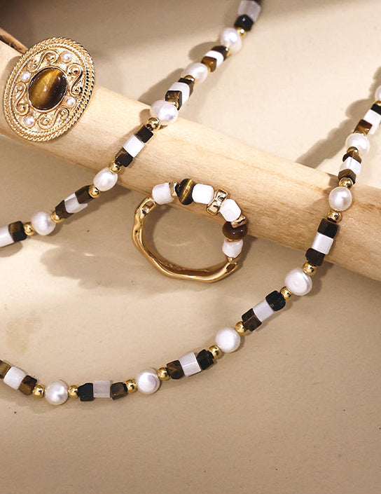 Gold-tone beaded ring close-up with white beads and dark accents