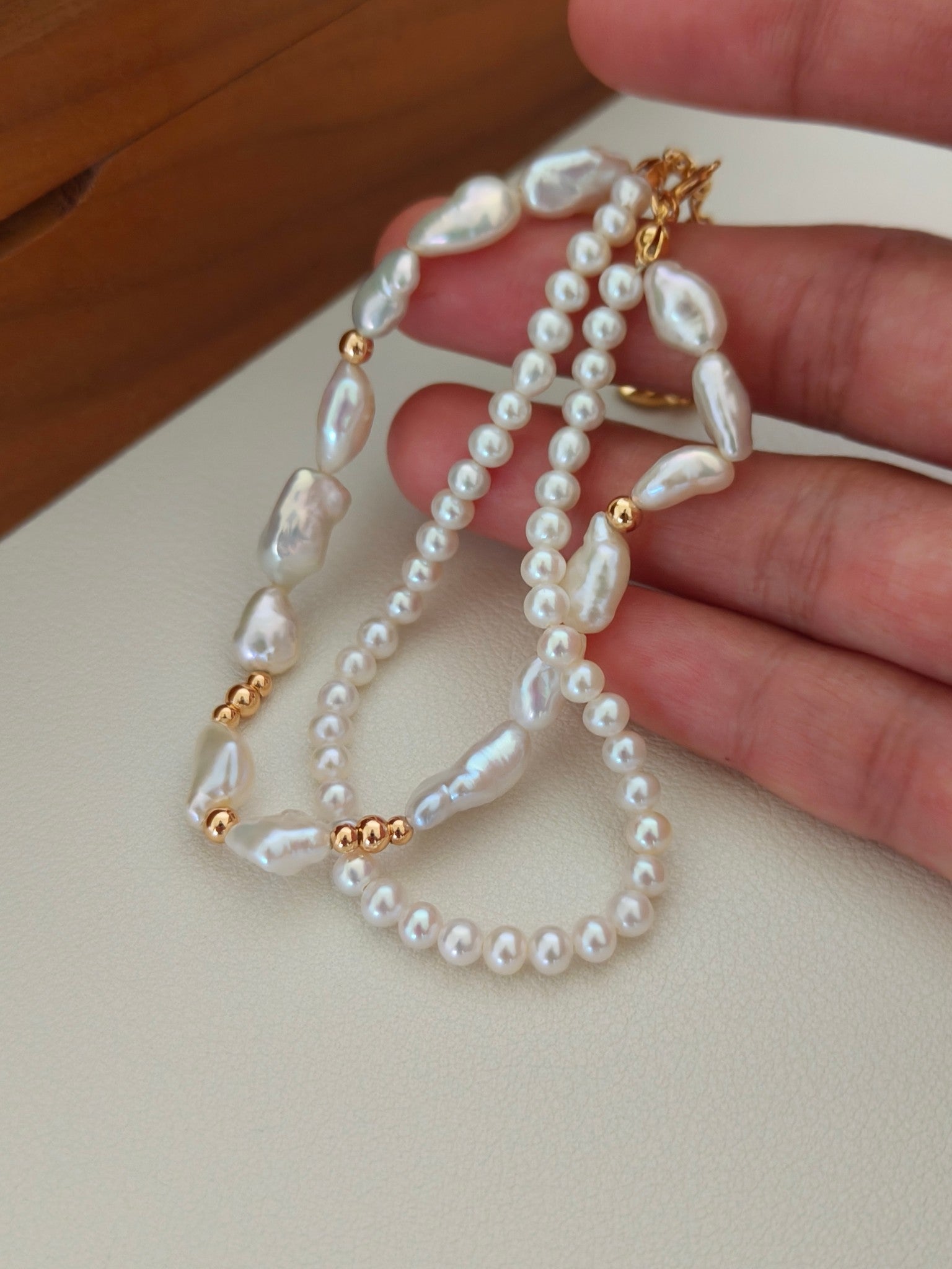 Freshwater pearl bracelet held in hand, featuring baroque pearls and gold connectors