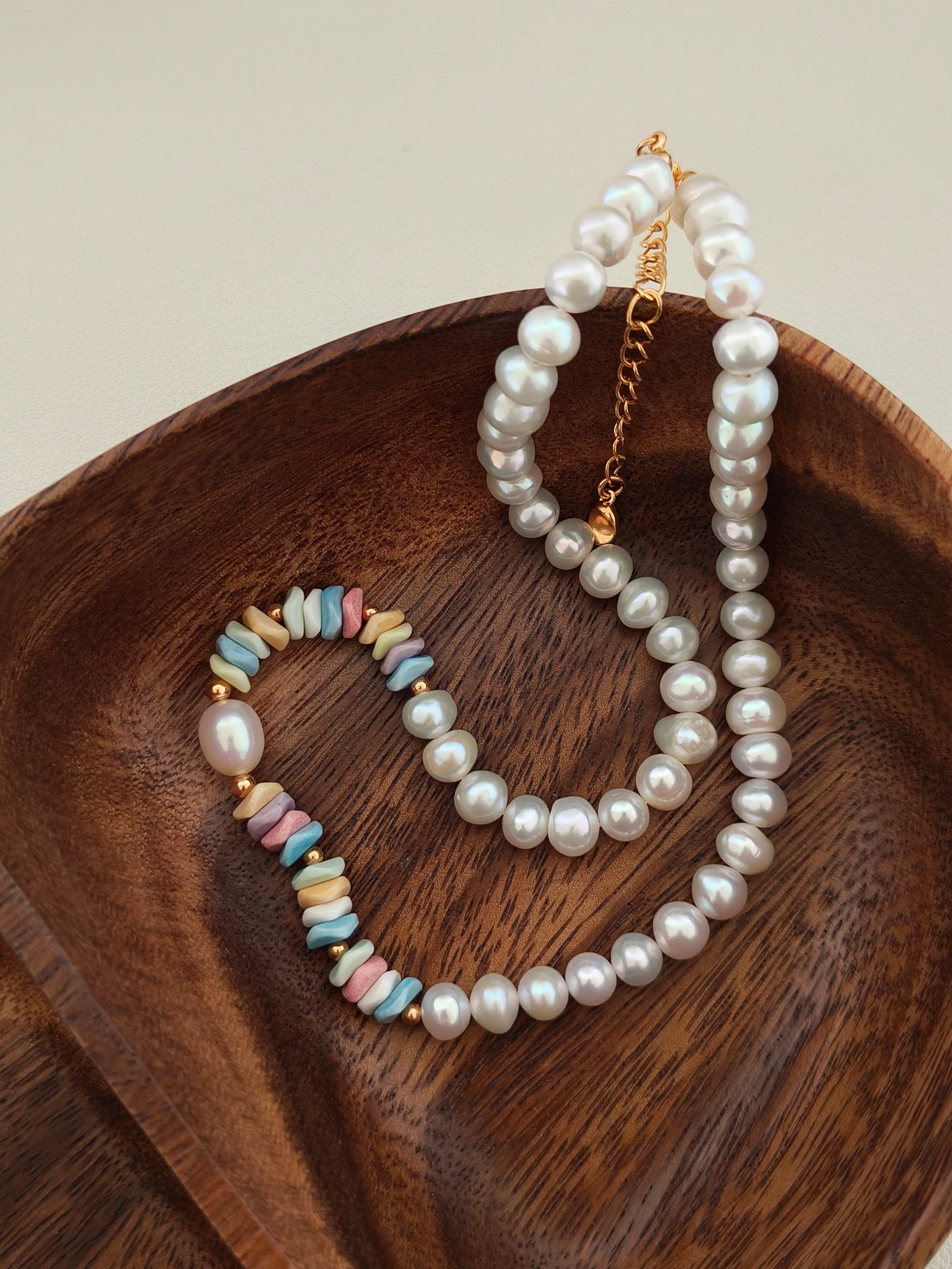 Stacked pearl necklace set showing rainbow bead accents and gold-toned chain.