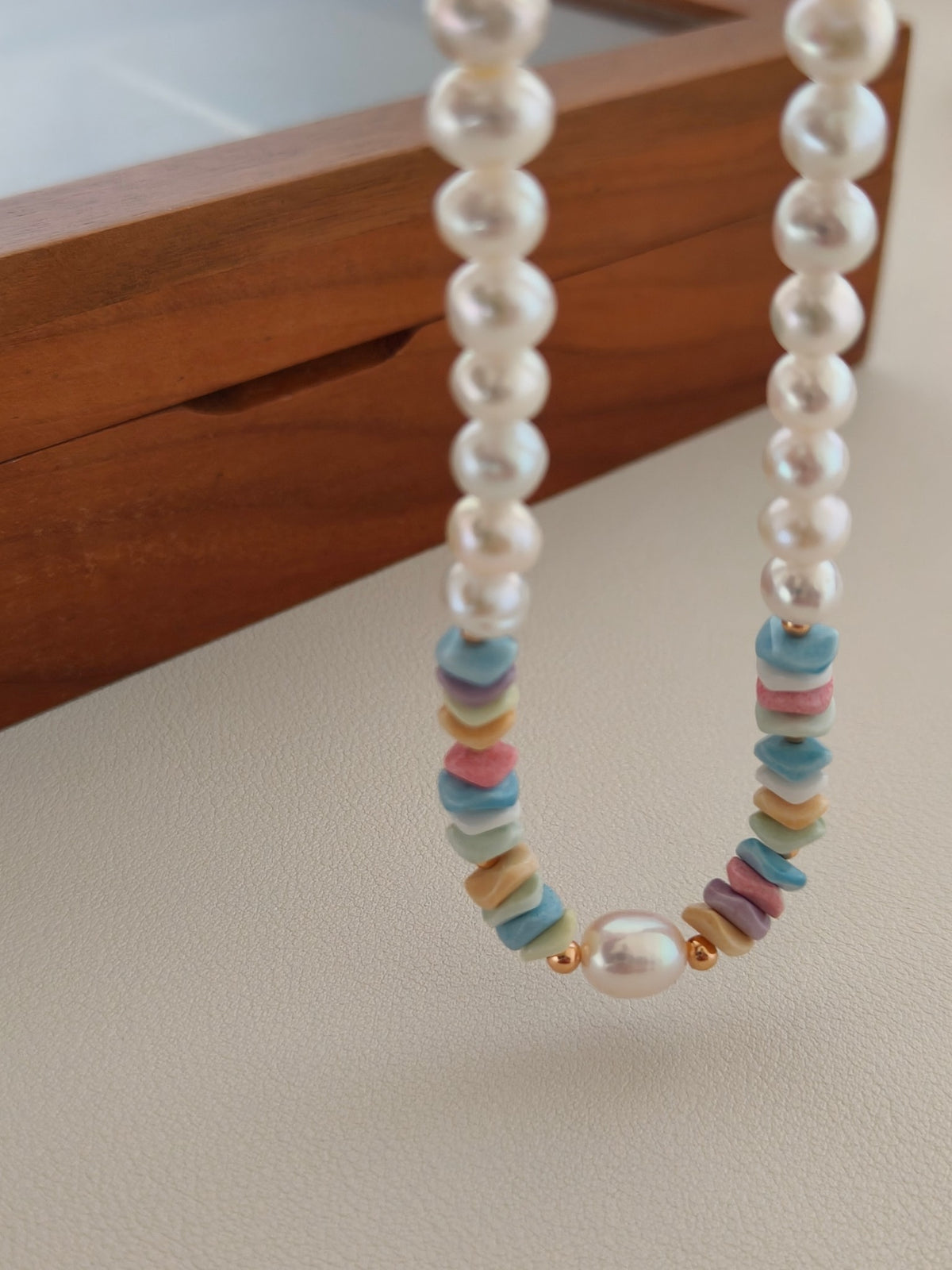 Close-up of freshwater pearl necklace with colorful rainbow stone bead fringe and clasp.