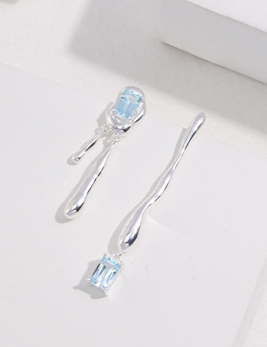 Silver-tone earrings with blue square gemstone, oval settings, and two-length drops