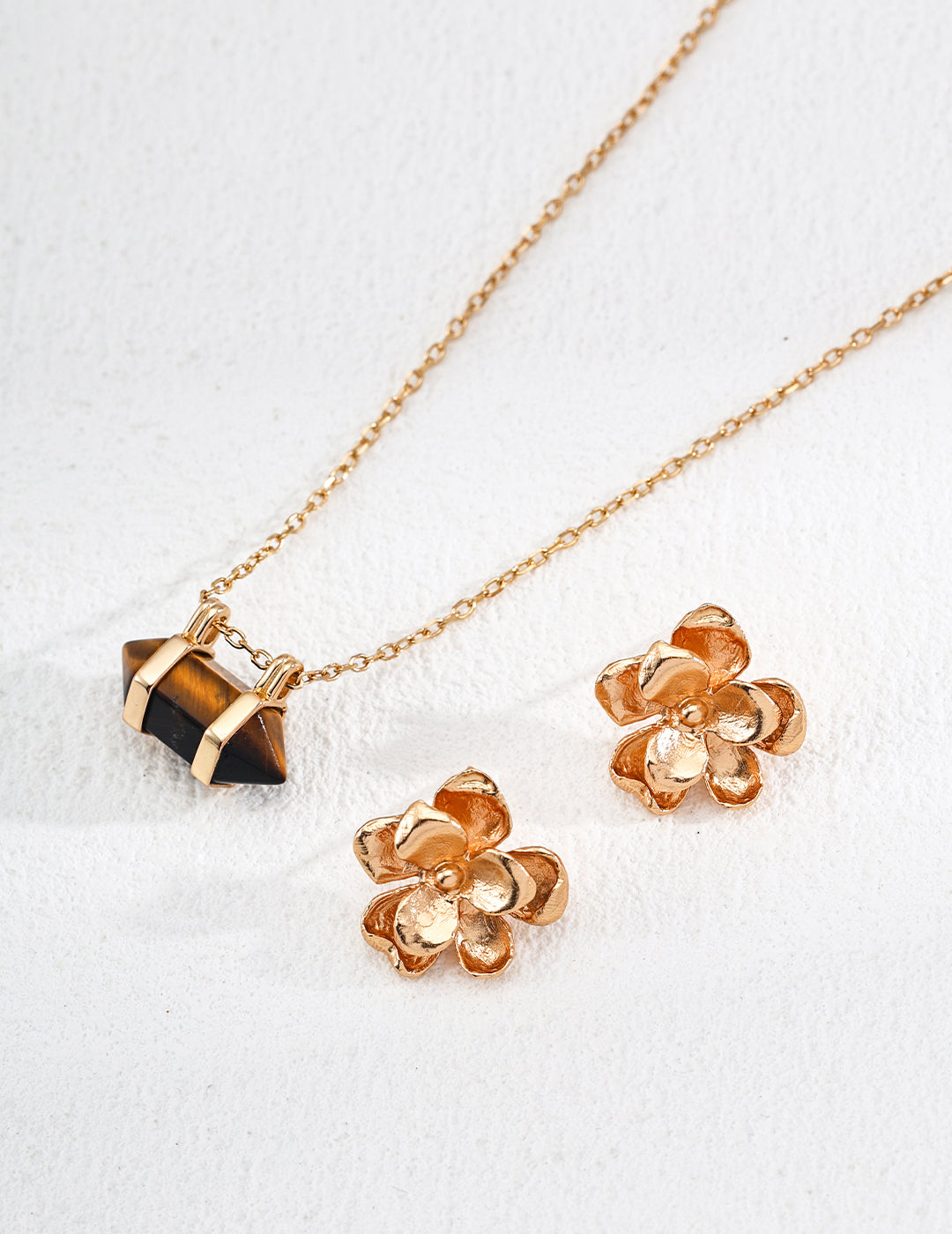 Gold chain necklace with a dark geometric stone pendant charm