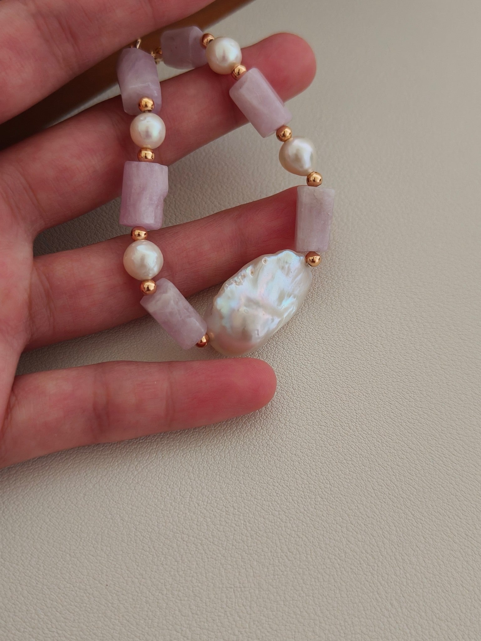 Purple stone, pearl bead, and bar-style bracelet shown in hand