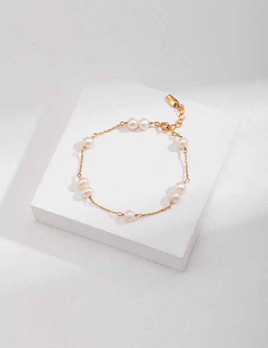 Gold-toned pearl bracelet with round white beads and a small teardrop charm
